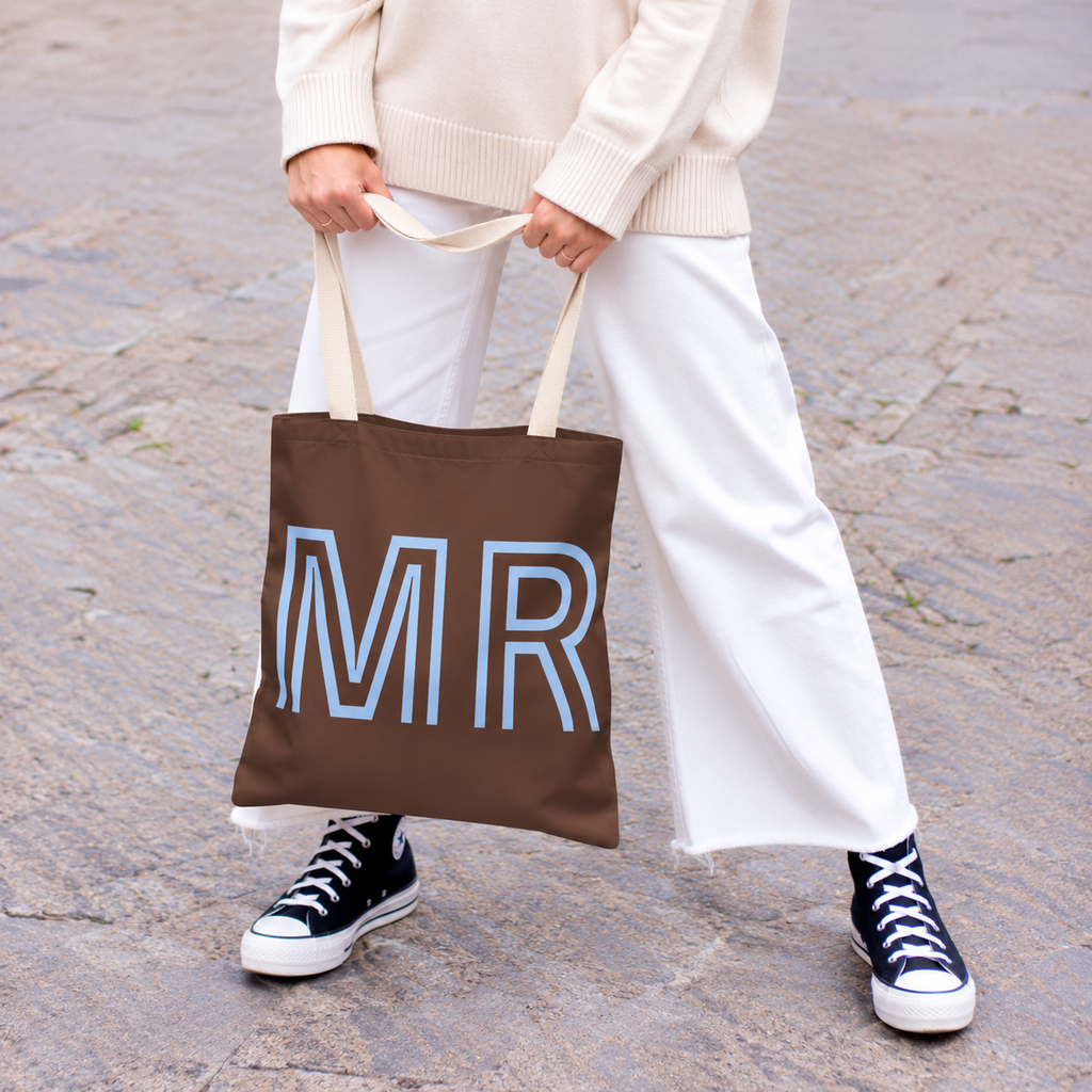 Woman in white trousers and sneakers holding the brown MR personalized tote bag