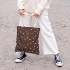 Woman holding the brown polka dot tote bag with blue dots in front of her on a street