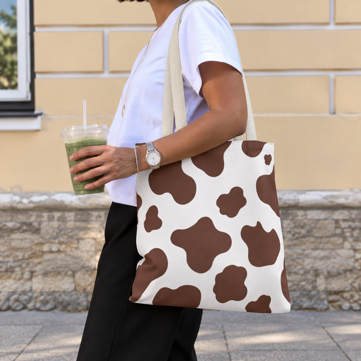 Side view of a woman wearing the brown cow print tote bag on her shoulder