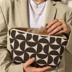 Hands holding the open brown cream geometric makeup bag