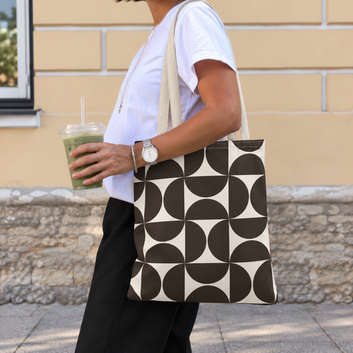 Side view of a person carrying the brown cream geometric tote bag on the shoulder