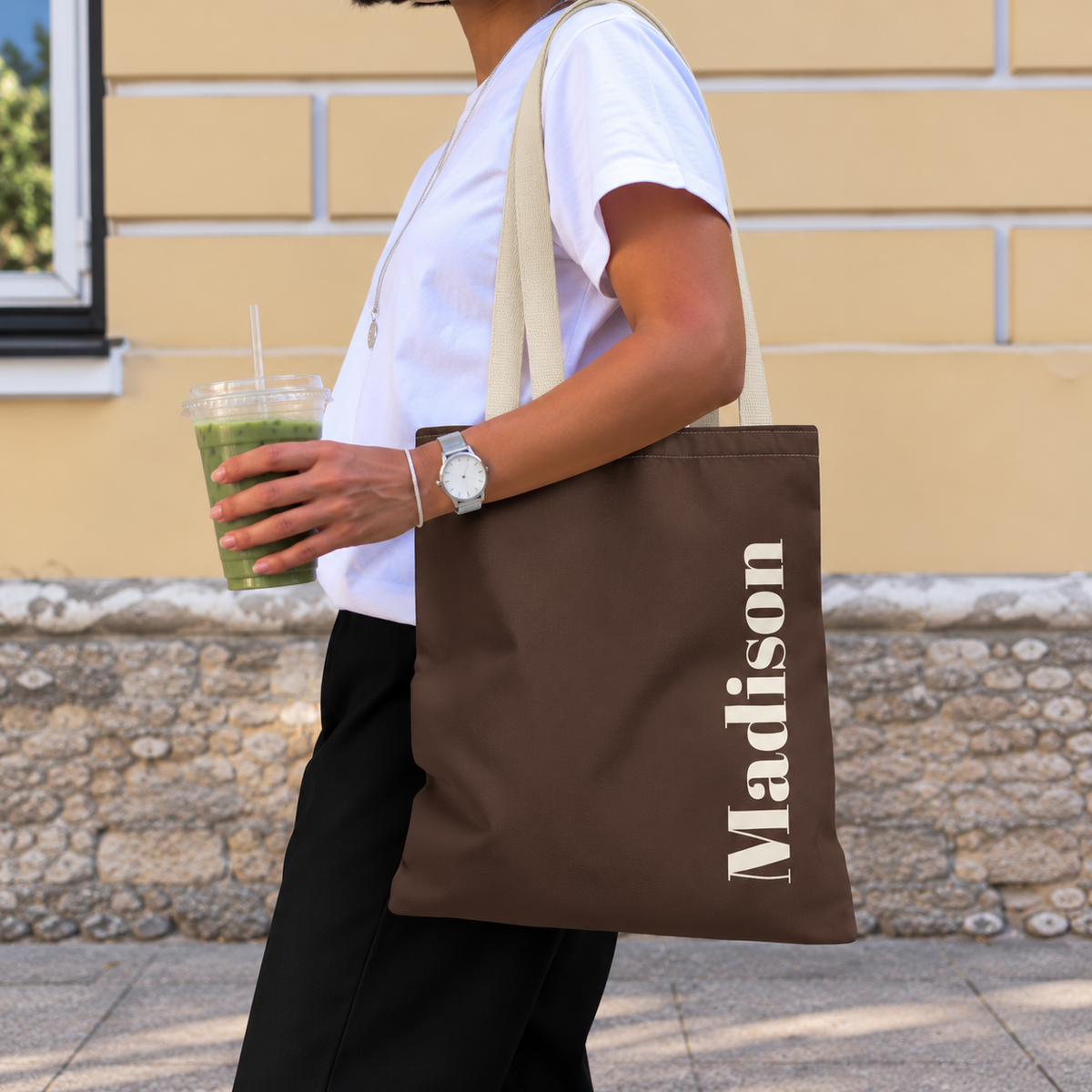 Woman carrying the Brown Cream Name personalized tote bag, side view with an iced drink