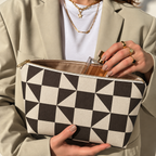 Hands holding the open brown cream triangle makeup bag