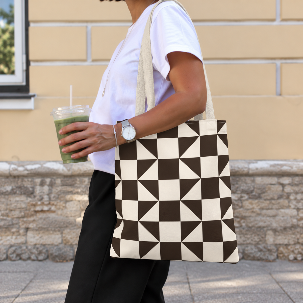 Side view of a person carrying the brown cream triangle tote bag on the shoulder