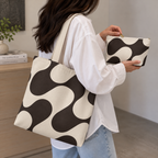 Woman carrying the brown wave tote bag and holding the matching makeup bag
