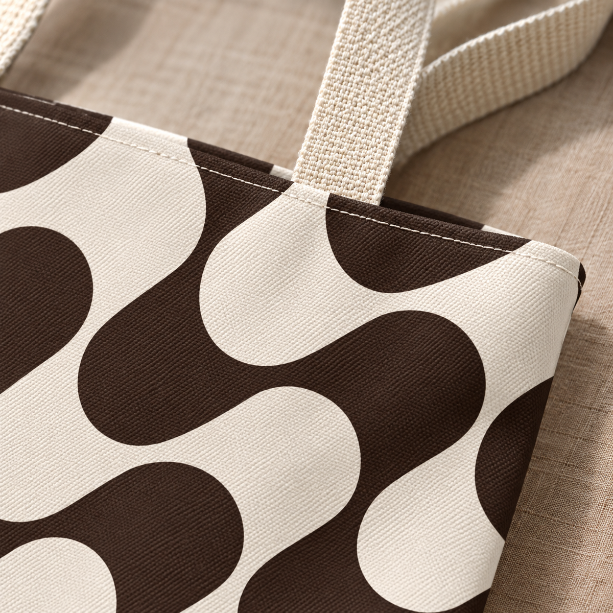 Close-up of the brown and cream wave print and the beige handle of the tote bag