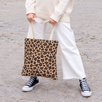Woman holding the brown leopard print tote bag in front of her on a street