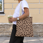 Side view of a woman wearing the brown leopard print tote bag on her shoulder