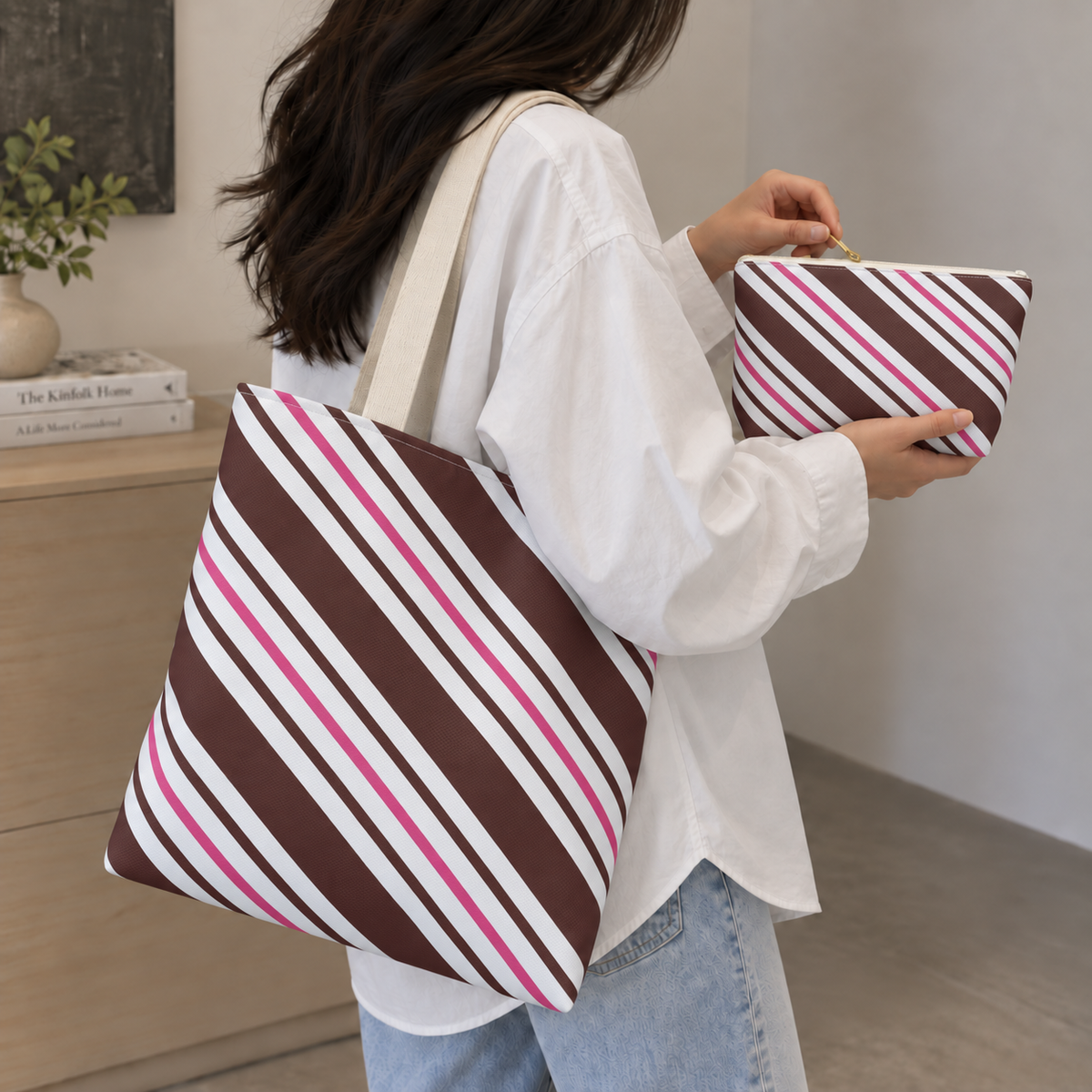 Woman carrying the brown pink diagonal striped tote bag with the matching makeup bag in her hand