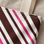 Close-up of the brown, pink and white diagonal stripes and the beige handle on the brown pink diagonal striped tote bag