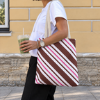 Woman carrying the brown pink diagonal striped tote bag on her shoulder on the street