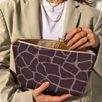 Hands opening a brown pink giraffe print makeup bag filled with cosmetics