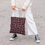 Woman holding a brown pink giraffe print tote bag with white trousers and sneakers