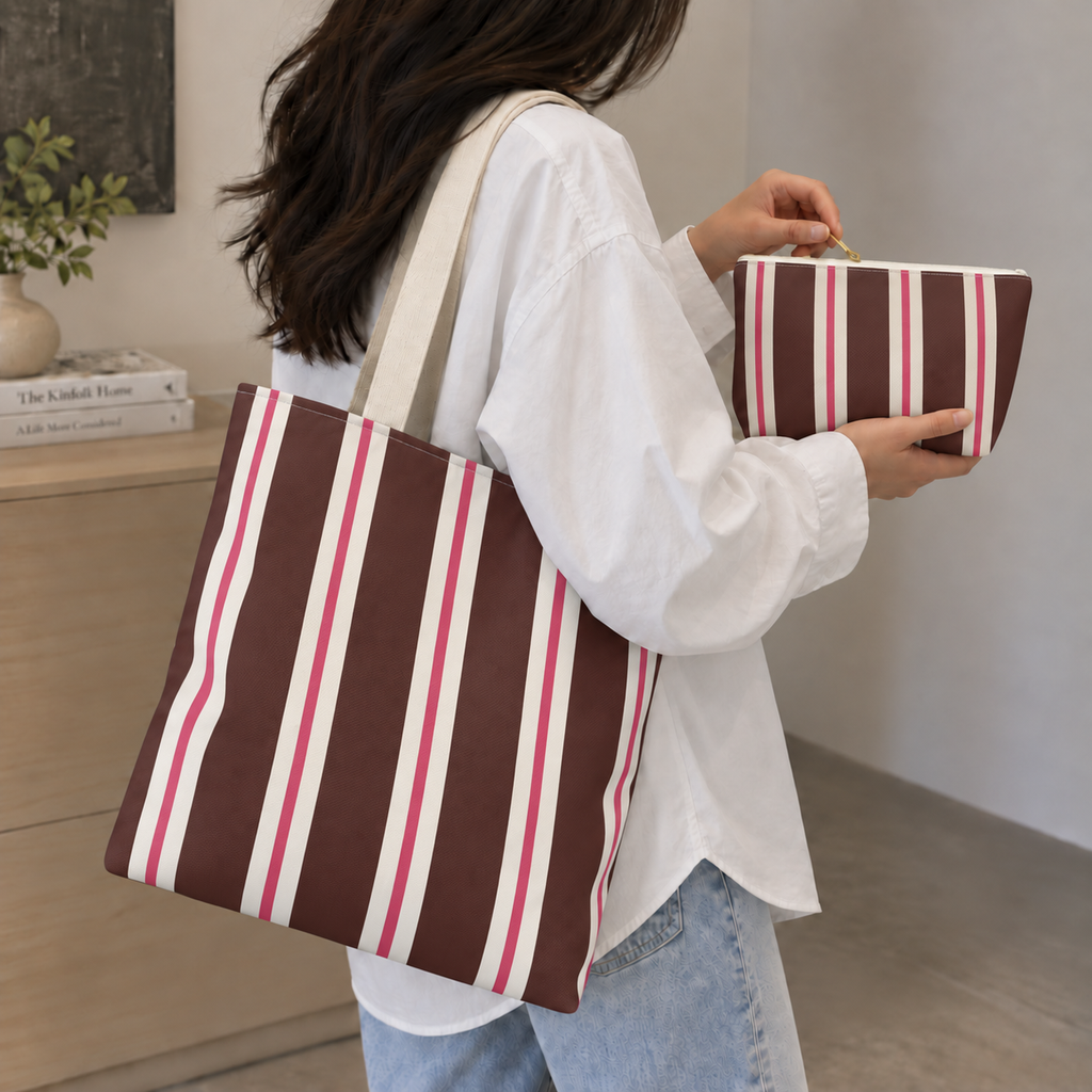 Woman carrying the brown pink striped tote bag with the matching makeup bag in her hand