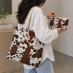Woman carrying a brown white cow print tote bag and matching makeup bag