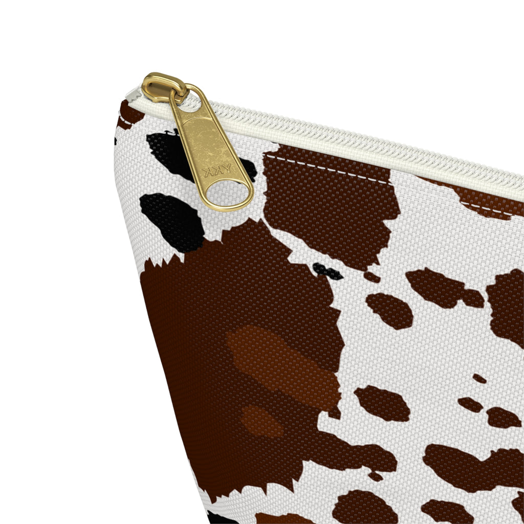 Close-up of the gold zipper pull and cow print patches on the makeup bag