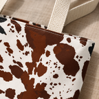 Close-up of brown and white cow print patches and the tote bag handle