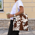 Woman walking with a cow print tote bag in brown and white over her shoulder
