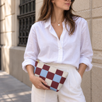 Woman in a white shirt holding the burgundy blue cream checkered makeup bag as a clutch