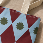 Close-up of the burgundy and blue diamond print with a green starburst and the tote handle