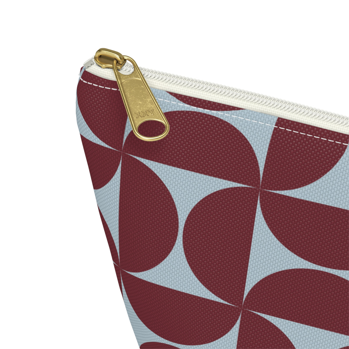 Close-up of the gold zipper pull and burgundy blue geometric print on the makeup bag