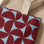 Close-up of the burgundy and light blue geometric print and the beige handle of the tote bag