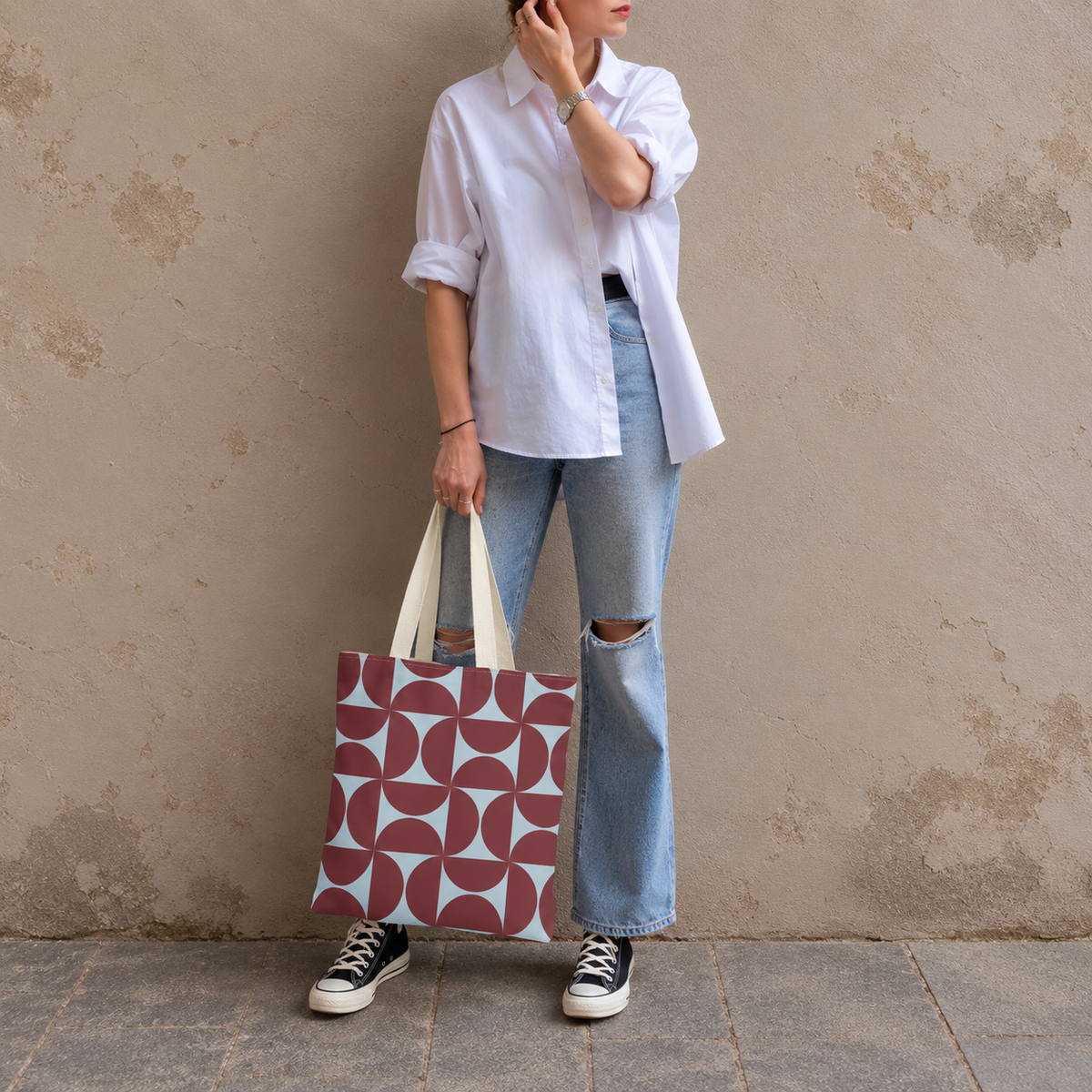 Woman in white shirt and jeans standing with the burgundy blue geometric tote bag
