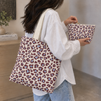 Model carrying the leopard print tote bag while holding the matching burgundy blue makeup bag
