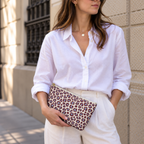 Woman in a white shirt holding the burgundy leopard print makeup bag at her hip