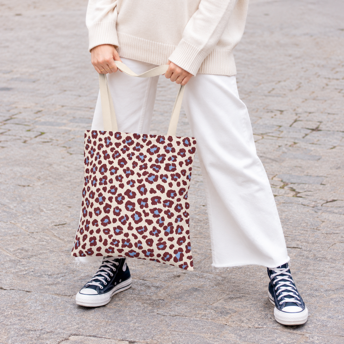 Woman holding the burgundy blue leopard print tote bag in front of her on a street