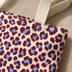 Close-up of the burgundy and blue leopard print rosettes and cream handle of the tote bag