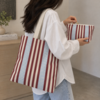 Woman carrying the burgundy blue pinstripe tote bag with the matching makeup bag in her hand
