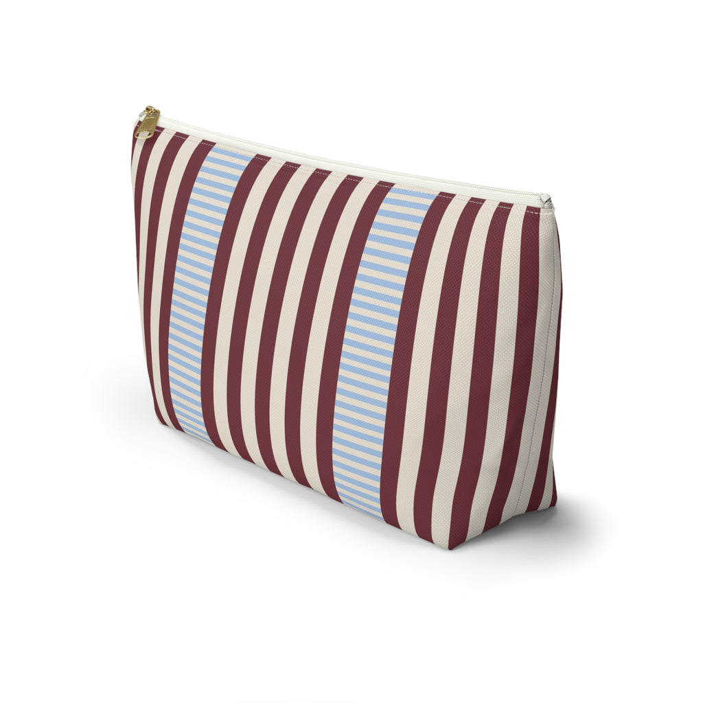 Side view of the burgundy blue pinstripe makeup bag standing on a white background