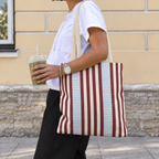 Woman carrying the burgundy blue pinstripe tote bag on her shoulder on the street