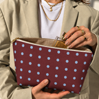 Woman opening the burgundy polka dot makeup bag to take out a perfume bottle