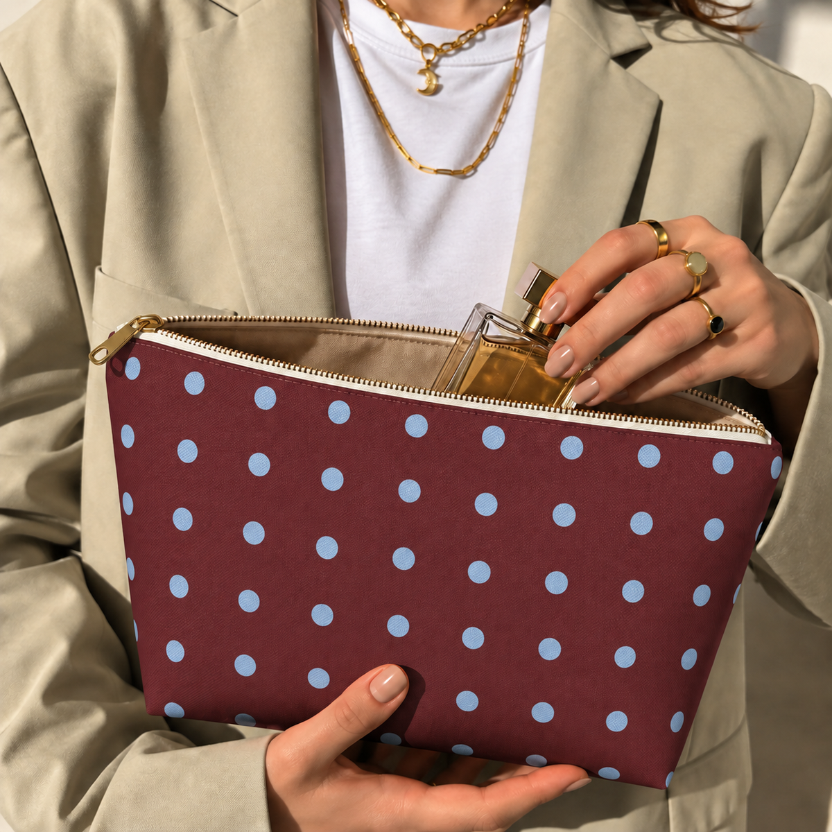 Woman opening the burgundy polka dot makeup bag to take out a perfume bottle