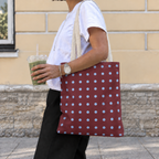 Side view of a woman carrying the burgundy blue polka dot tote bag on her shoulder