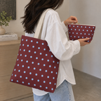Model carrying the burgundy polka dot tote bag with the matching makeup bag in hand