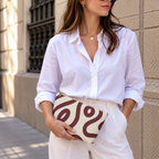 Woman in white shirt holding the burgundy cream abstract makeup bag