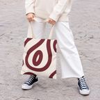 Woman in white trousers holding the burgundy cream abstract tote bag by the handles