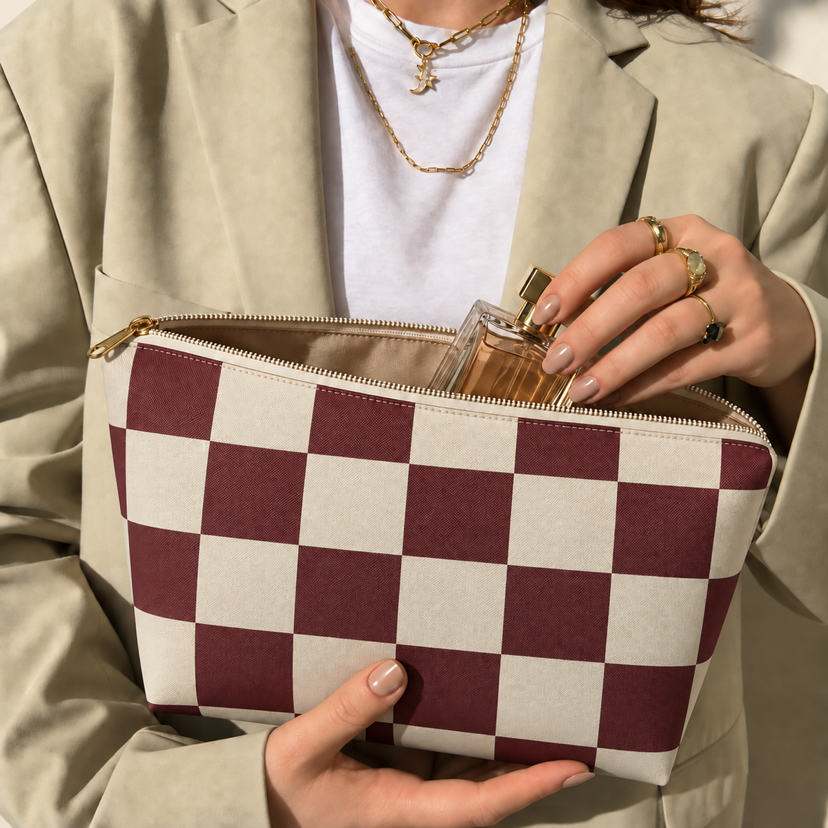 Hands holding the open burgundy cream checkered makeup bag