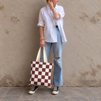 Woman in white shirt and jeans standing with the burgundy cream checkered tote bag