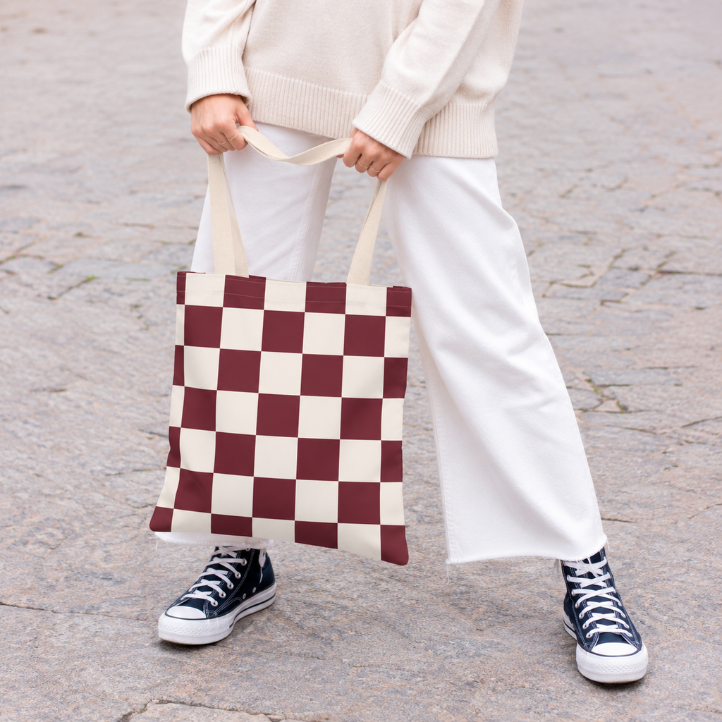Woman in white trousers holding the burgundy cream checkered tote bag by the handles