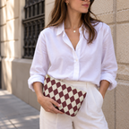 Woman in a white blouse holding a burgundy cream diamond checkered makeup bag