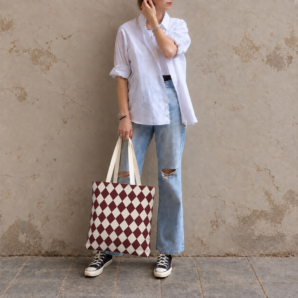 Woman leaning on a wall with a burgundy cream diamond checkered tote bag