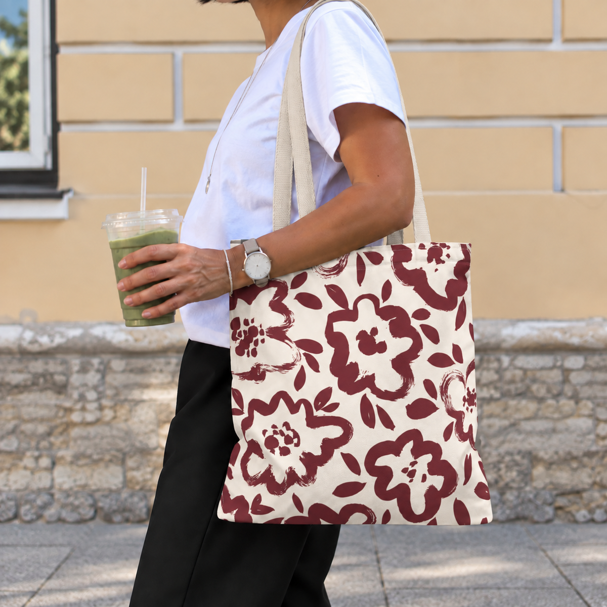 Side view of a person carrying the burgundy cream floral tote bag on the shoulder