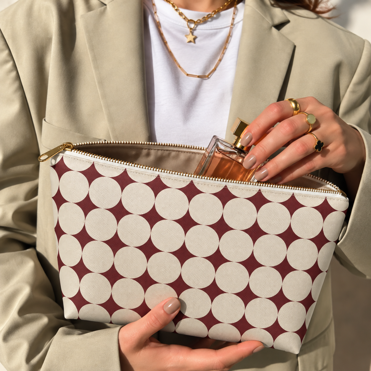Hands holding the open Burgundy Cream Geometric makeup bag filled with cosmetics