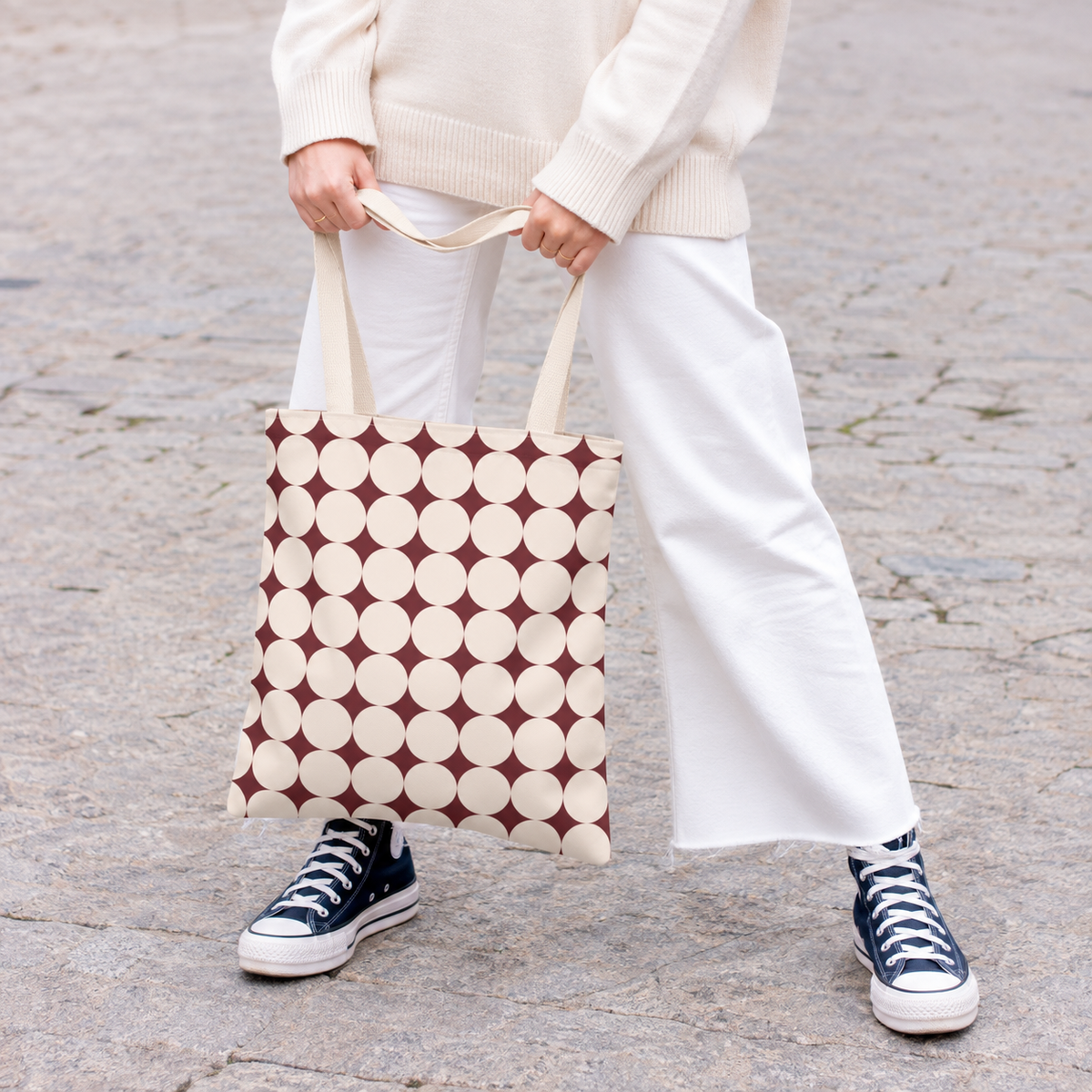Woman carrying the Burgundy Cream Geometric tote bag in white trousers on a city street