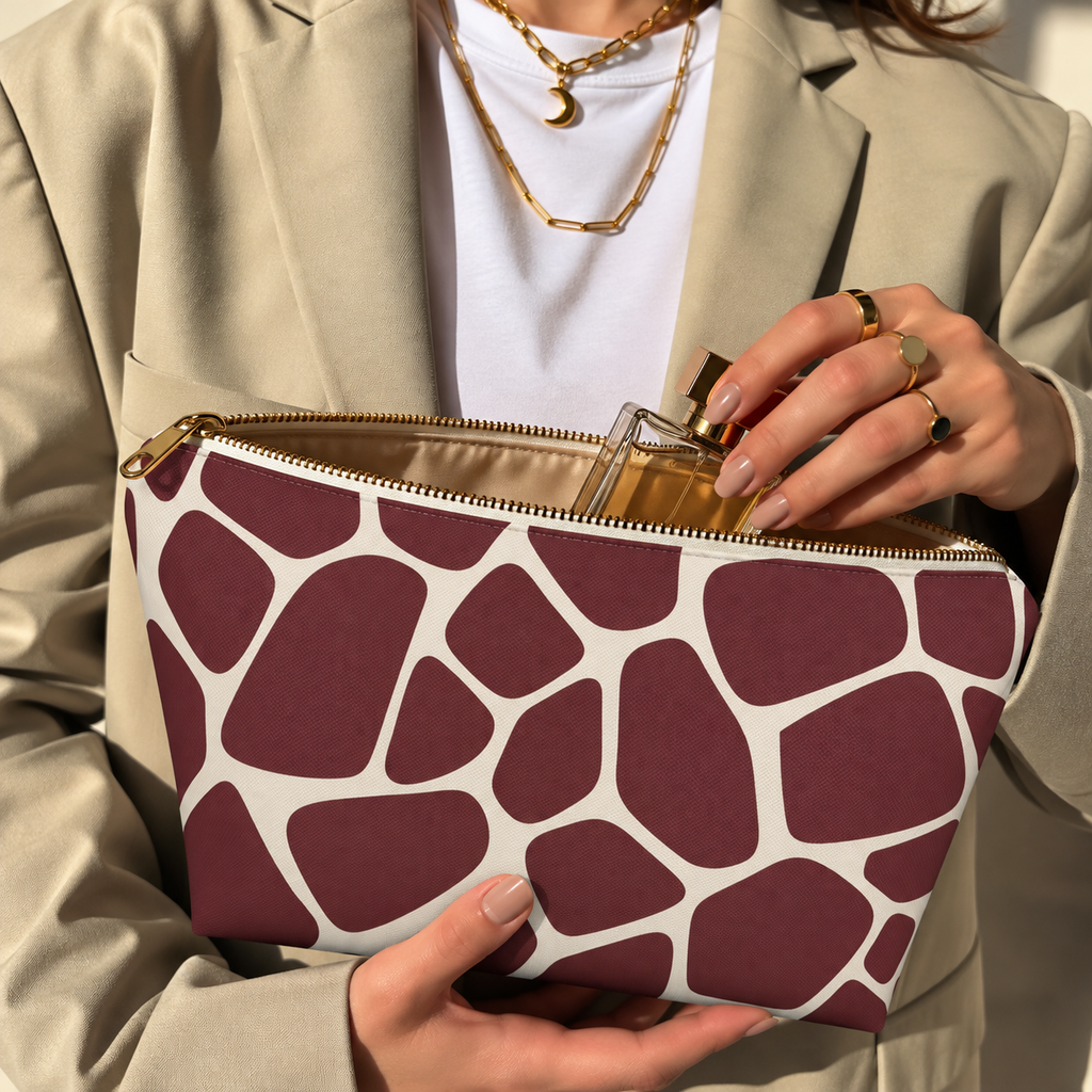 Hands opening a burgundy cream giraffe print makeup bag filled with cosmetics