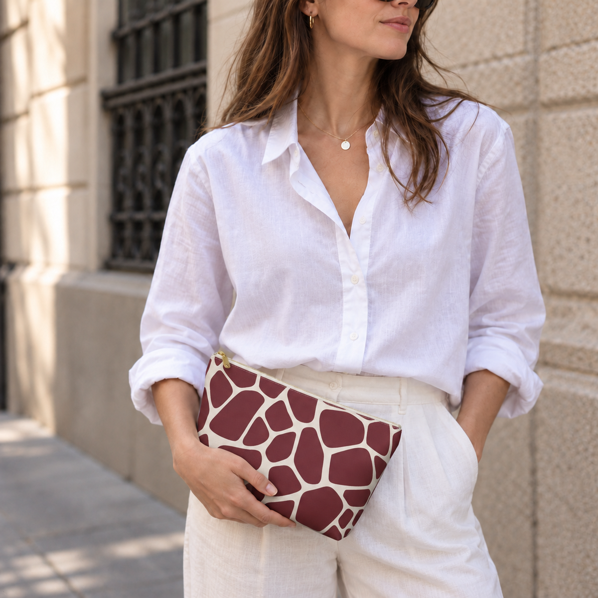 Woman holding a burgundy giraffe print makeup bag like a clutch